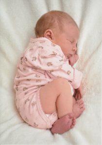 Sleeping baby wearing a pink onesie.