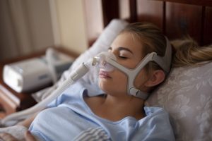 Woman lying in a hospital bed wearing a breathing mask.