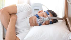 Man lying in a hospital bed wearing a breathing mask.